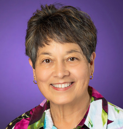 Dr. D Lynn Jackson poses in front of a TCU Purple backdrop
