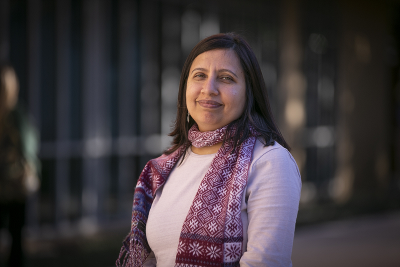 Dr. Aesha John, an associate professor of social work, posing in front of a building.